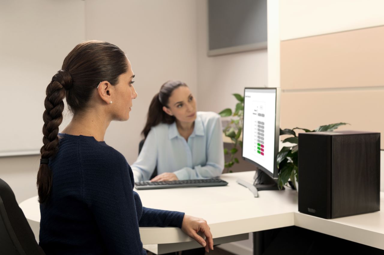 Una donna con apparecchio acustico BTE con una professionista Amplifon che sta eseguendo il test dell'udito.