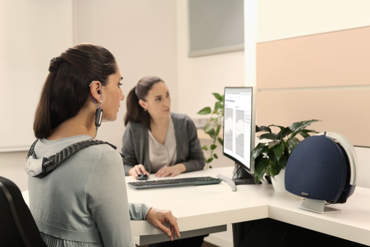 Femme portant un appareil de test, une experte Amplifon interprétant les résultats