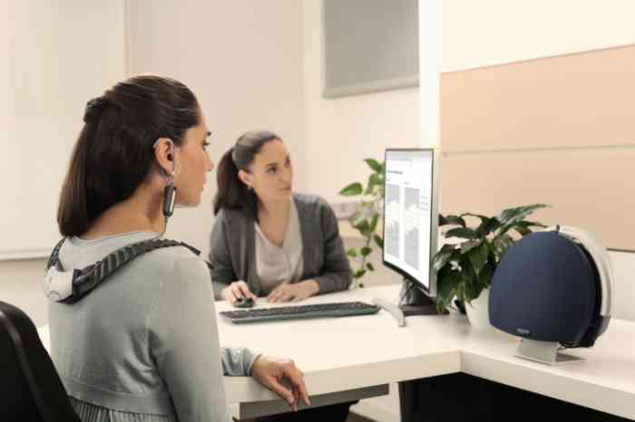 Una donna indossa un dispositivo per il test dell'udito e una professionista Amplifon analizza i risultati.