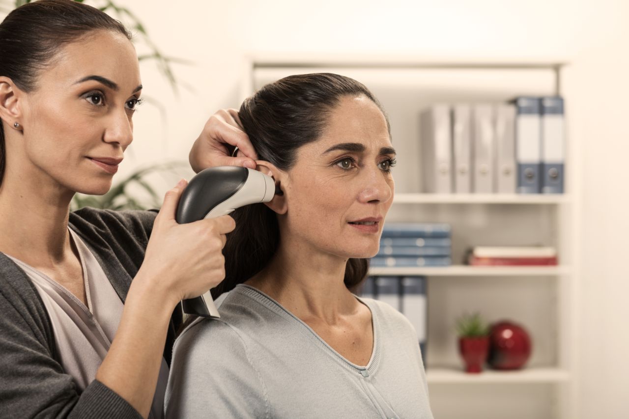 Une femme sans blouse place une seringue manuelle sur l'oreille.