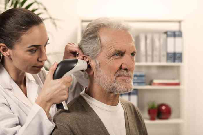 Audiologo esamina l'orecchio di un uomo anziano con un video otoscopio.
