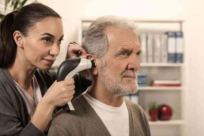 Audiologo esamina l'orecchio di un uomo anziano con un video otoscopio.