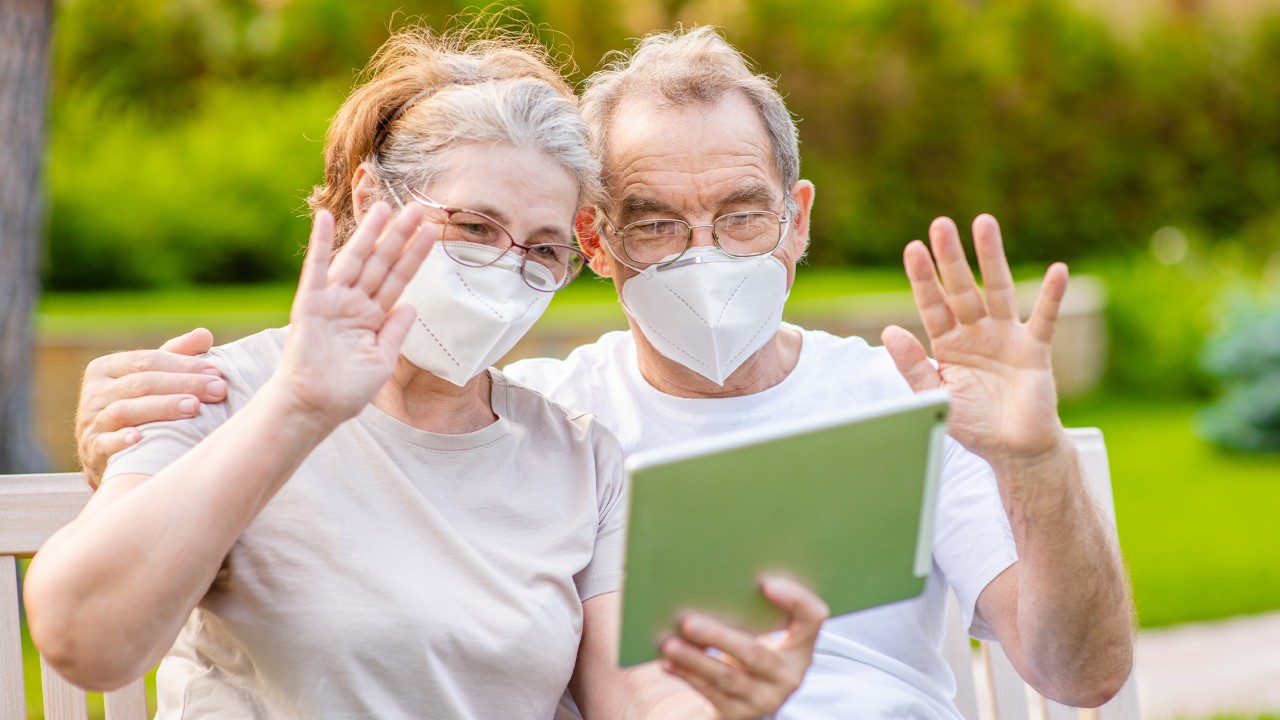 couple avec masque et tablette dans le jardin
