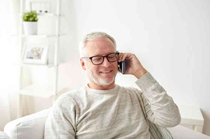 Homme senior portant des lunettes en train de converser au téléphone.