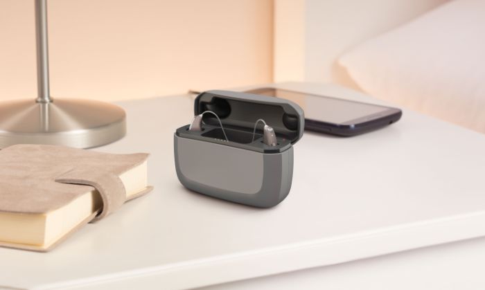 Un boîtier de recharge pour appareil auditif de couleur grise posé sur un table.