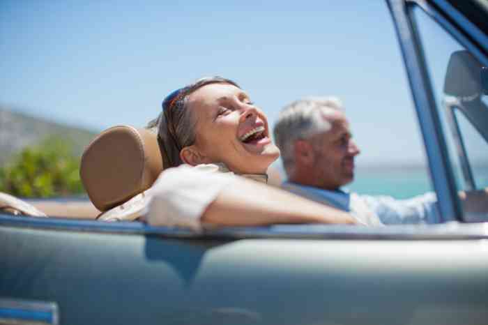 A senior couple enjoying their time and smiling on their car