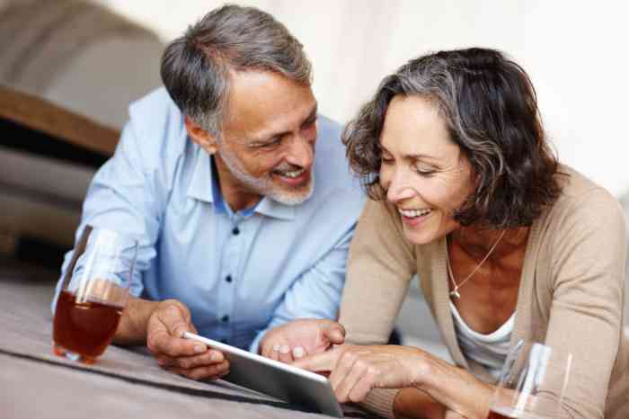 Couple senior souriant consultant une tablette tactile.