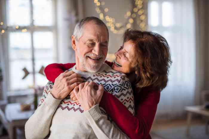 Couple s'embrassant et se souriant dans une maison décorée sur le thème de Noël. 