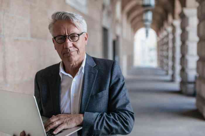 Senior man with glasses holding his laptop