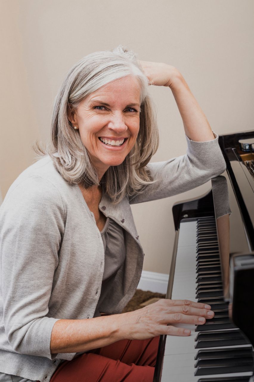 Frau lächelt und spielt Klavier.