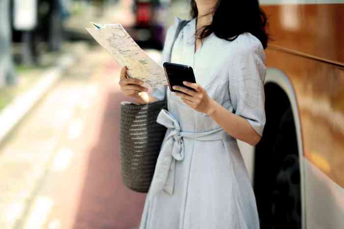 A young turist with a smartphone and a map in her hands