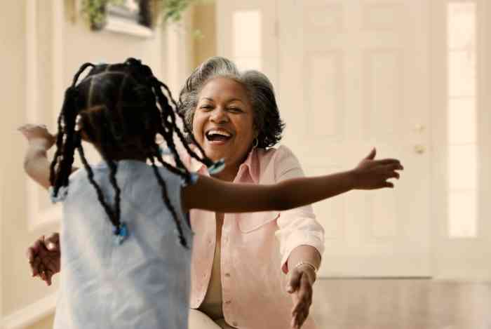 A grandmother smiling and hugging her granddaughter