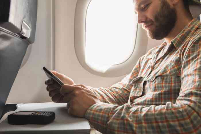 Man gebruikt zijn mobiele telefoon in een vliegtuig
