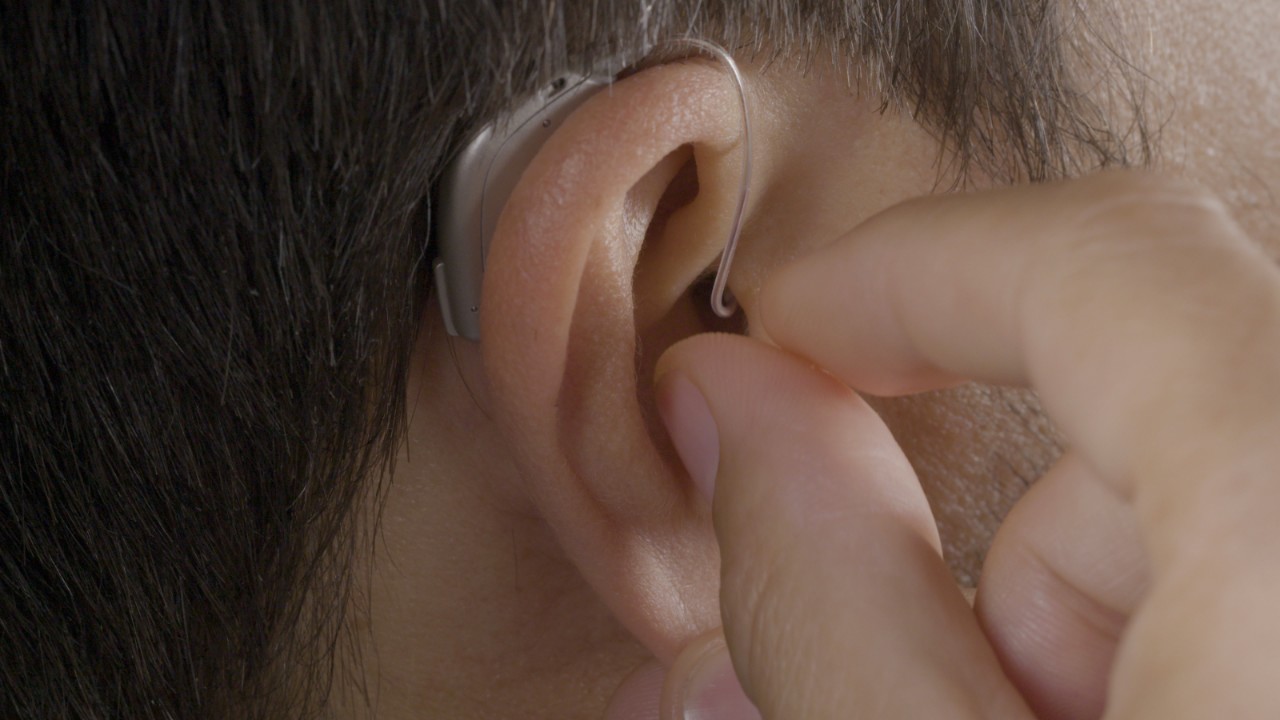 A woman connects her smart hearing aid to her tablet holding a conversation in a videocall
