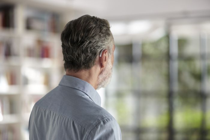 Senior woman with Behind-The-Ear hearing aid looking at Amplifon app