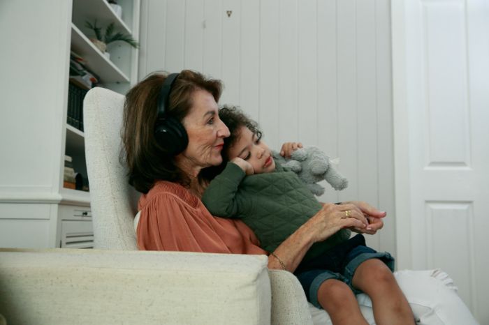 Nonna con cuffie acustiche mentre tiene in braccio il nipote
