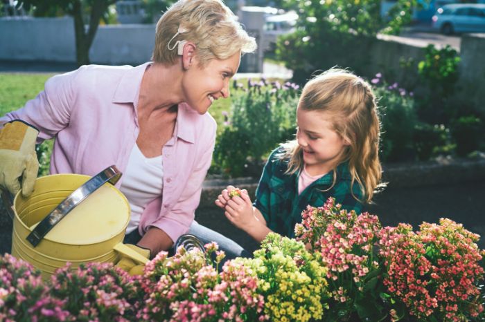Grand-mère portant un aide auditif dans le jardin avec sa petite fille