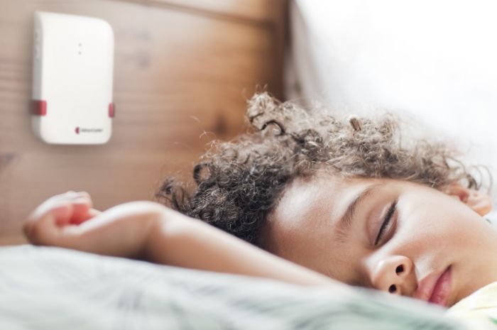 Un bambino riposa con una sveglia acustica vicino a sé