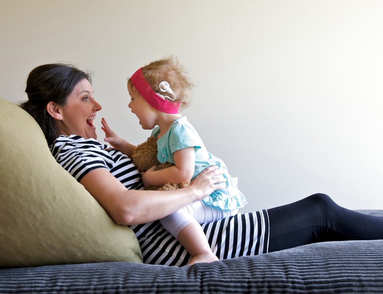 Ein kleines Mädchen spielt mit seiner Mutter auf dem Sofa