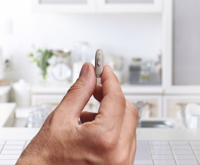 Apparecchio acustico beige in una mano