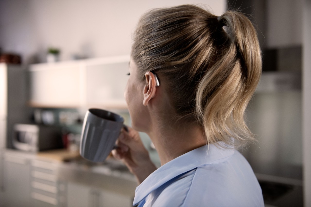 vrouw met hoorapparaat drinkt koffie