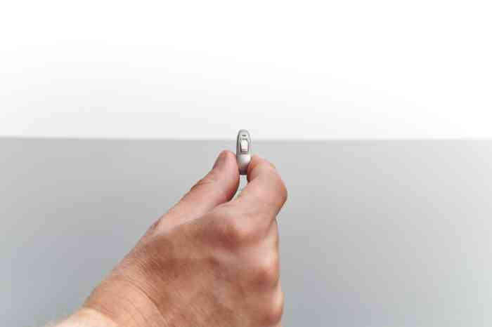 Une main présentant un appareil auditif invisible 