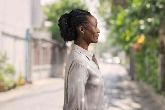 Profil d'une femme avec une chemise beige et un appareil RIC Amplifon en extérieur.