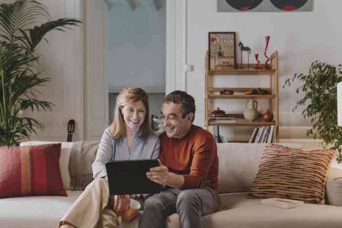 Couple senior souriant consultant une tablette tactile.