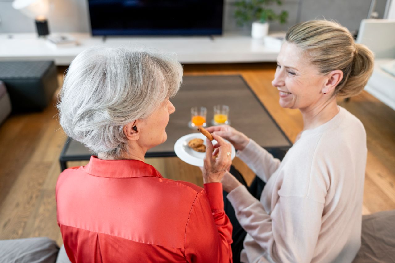 Une femme âgée et une femme plus jeune trinquent dans un salon.