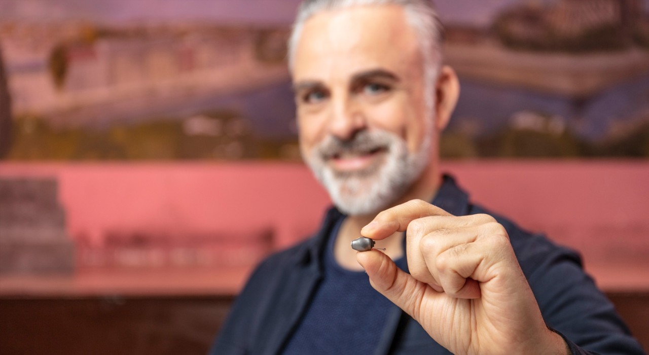 Un homme tient une aide auditive