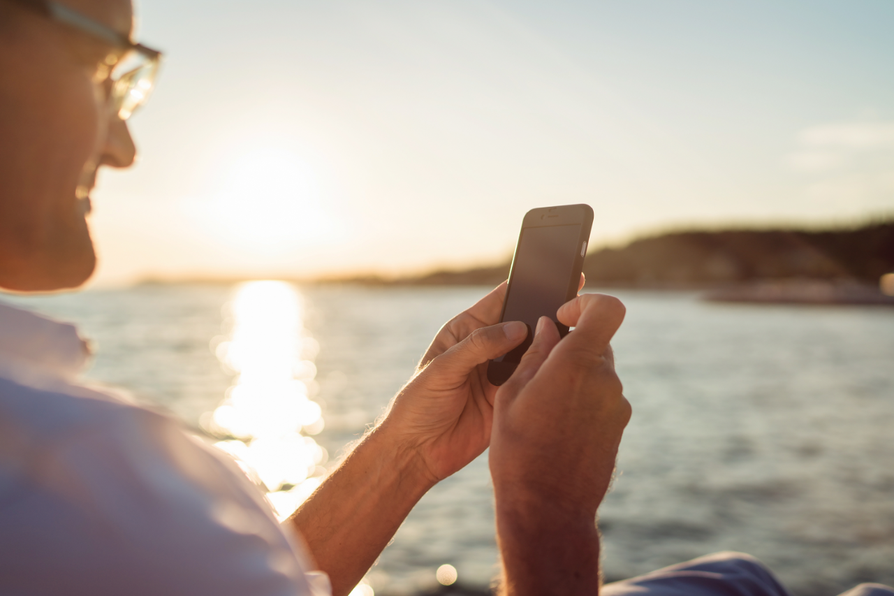 Homme sur la plage au coucher du soleil tenant un téléphone