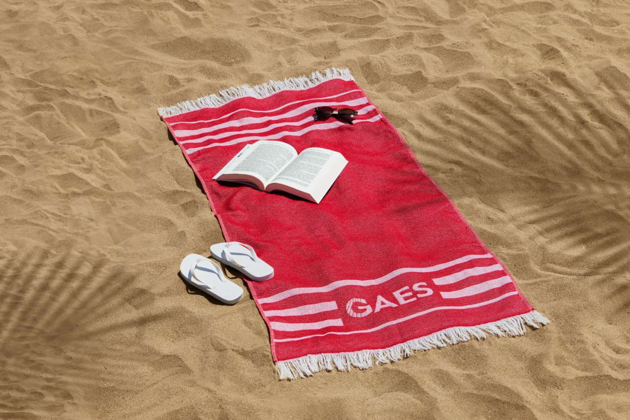 Serviette de plage avec livre, lunettes de soleil et chaussures de bain