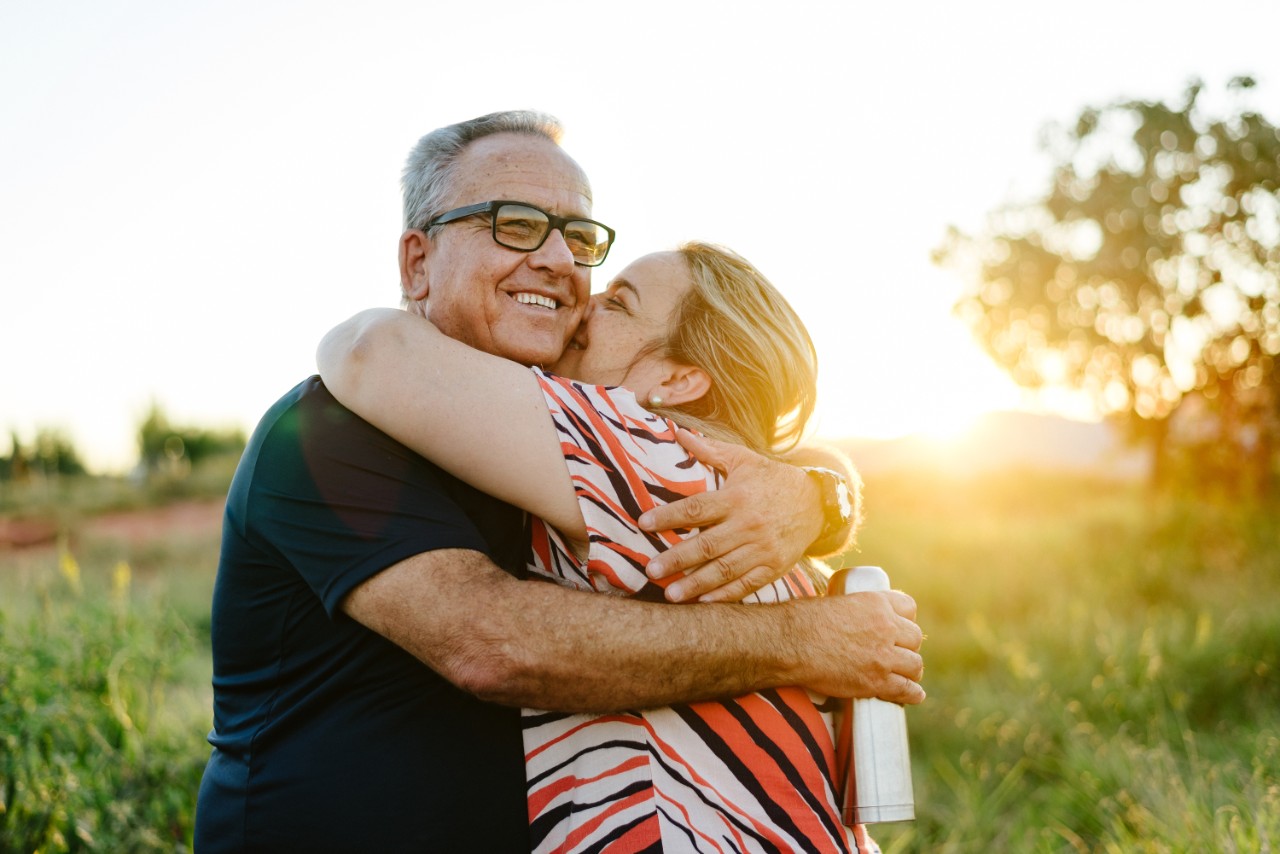 Couple souriant s'embrassant dans une prairie.