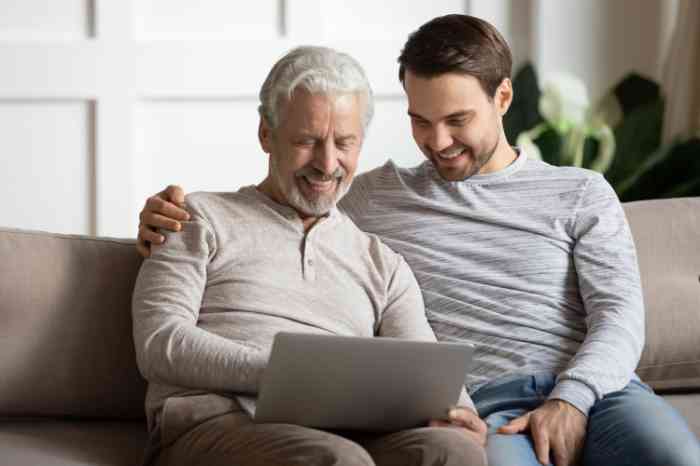 A dad and a son watching something in the pc. 