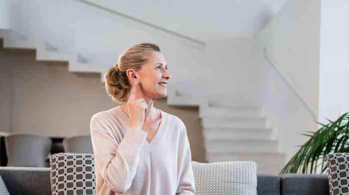 Femme avec un appareil auditif assise sur le canapé