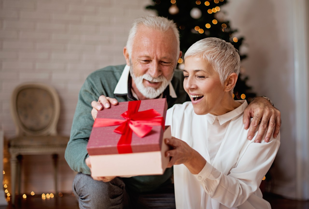 Couple souriant en ouvrant un cadeau de Noël. 